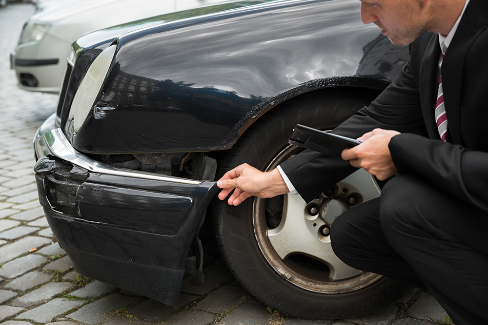 Insurance agent inspecting car involved in accident